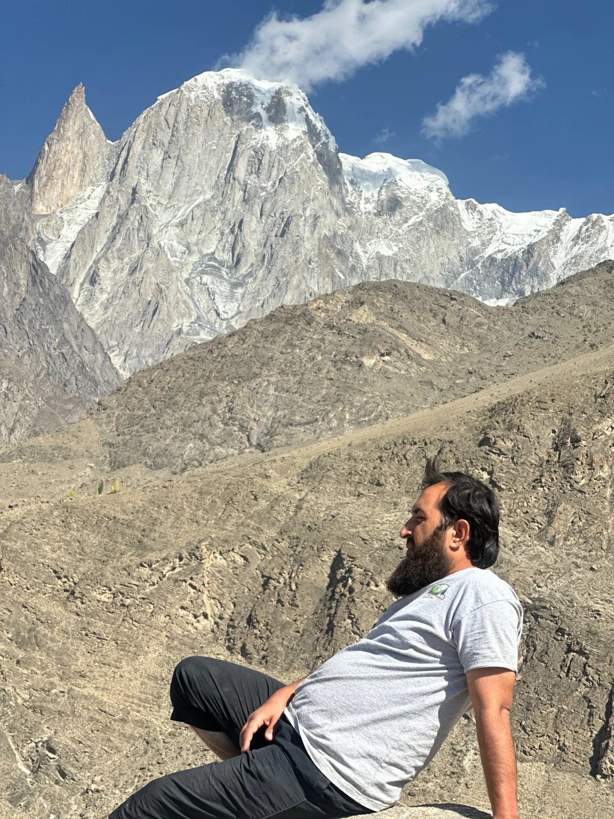 Abdullah resting on rocks beneath a jagged mountain peak