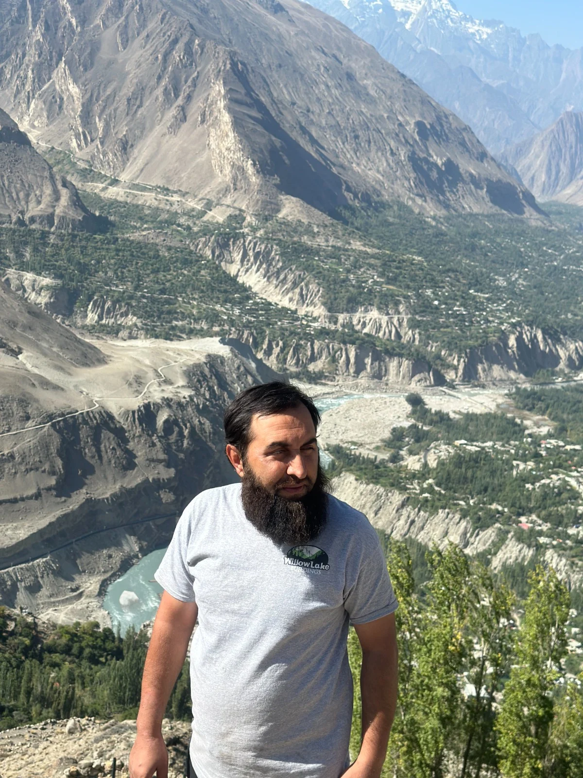 Abdullah standing above a valley with steep rocky mountains