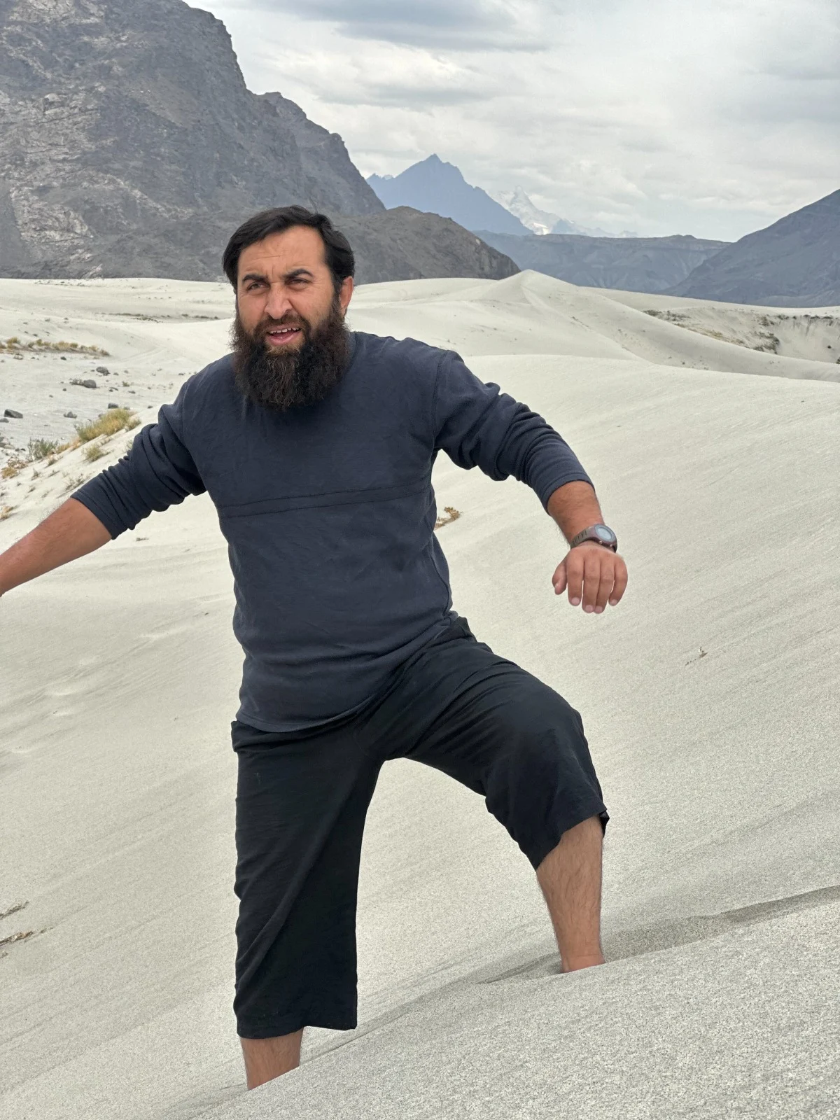 Abdullah climbing a sandy slope in a mountain landscape