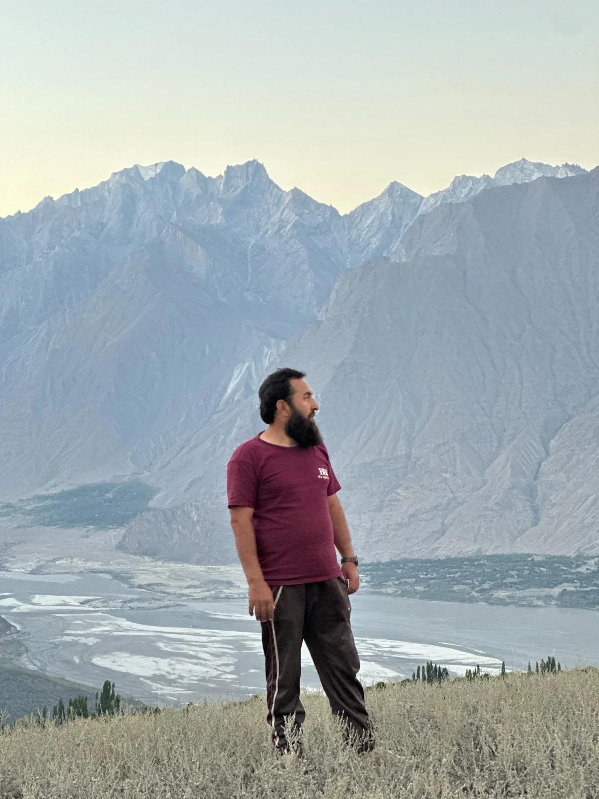 Abdullah standing above a broad river valley beneath a long mountain ridge