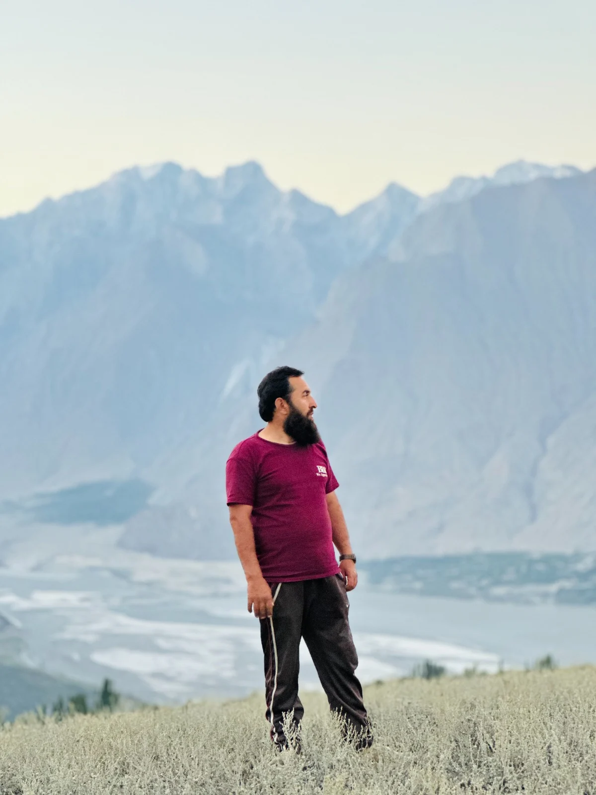 Abdullah surrounded by meadow grasses with mountains in the distance